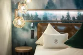 Modernes Hotelzimmer mit Waldtapete, Lederkopfteil und dekorativer Beleuchtung